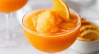 this image show a glass that is filled with Frozen Aperol Spritz With Frozen Oranges