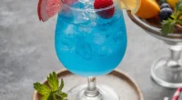 this image shows a glass full with Blue Lagoon Mocktail that is garnish with cherry and half cut lemon
