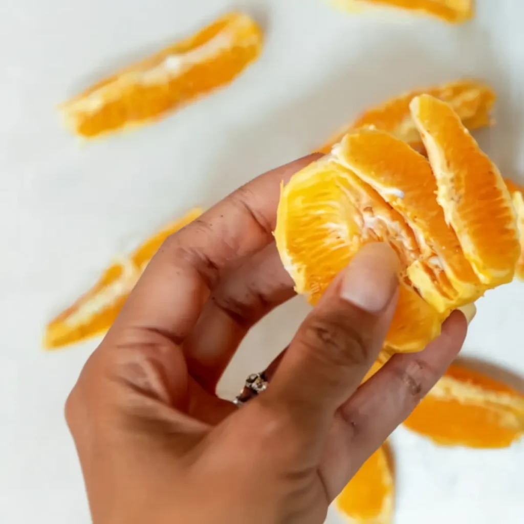this image shows a orange is being peeled by a lady