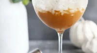 this image shows the side view of a wine glass full with Pumpkin Spice Martini With Whipped Cream